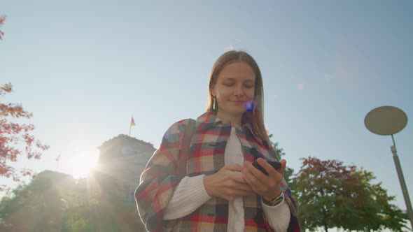Happy Woman Uses By Smartphone App Outside Near Bundestag in Berlin in Autumn