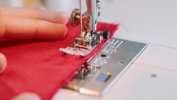 Hands of Woman Tailor Sewing Red Clothing on Sewing Machine with Straight Seam alt