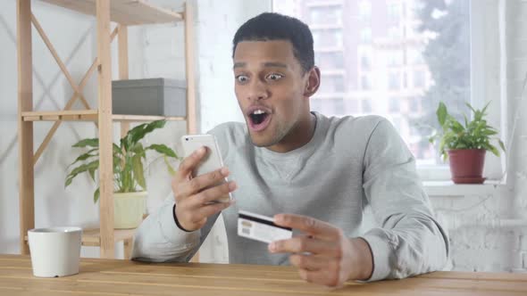 Online Shopping By Excited AfroAmerican Man Payment on Smartphone alt