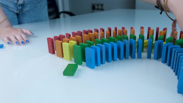 Line up of Dominoes in Rainbow Falling Colors with LGBT Colors of a Hand alt
