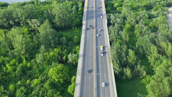 Aerial view of car traffic on modern bridge over river in city in summer day alt