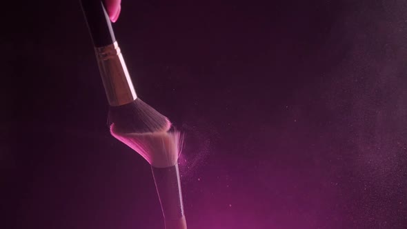 Two Makeup Brushes Closeup with Pink Powder on a Black Background Slow Motion