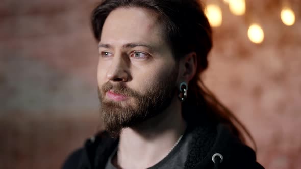 Portrait of a Surprised Man Bearded with Long Hair and Large Earrings in His Ears alt