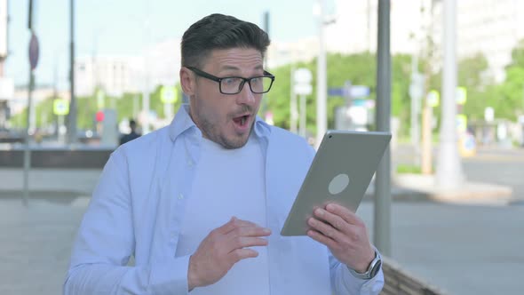 Man Celebrating Online Win on Tablet Outdoor alt