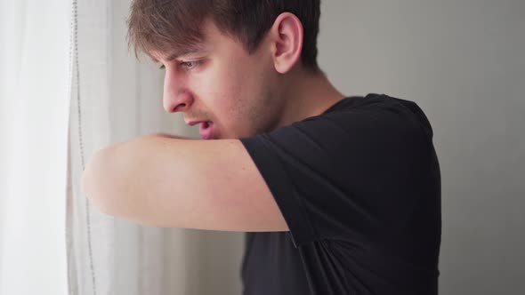 Young Man Coughing Into His Arm or Elbow To Prevent Spread Virus. Close-up Static Shot