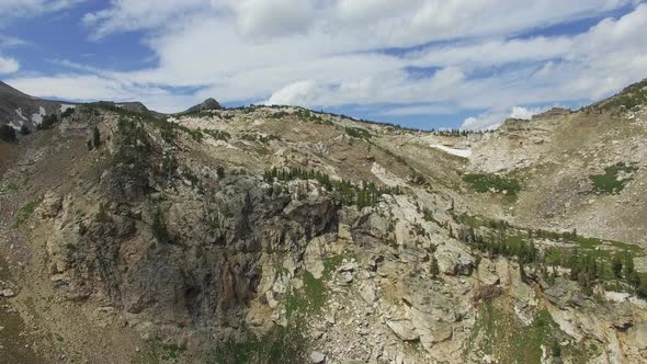 Mountain peaks are revealed as the camera flies away from mountainside alt