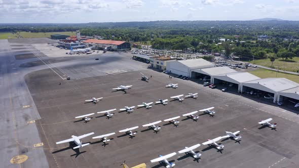 Large number of light aircraft parked on tarmac, Cibao Airport; aerial alt