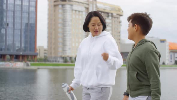 Sportive Asian Mother and Son Chatting and Drinking Water after Morning Run alt