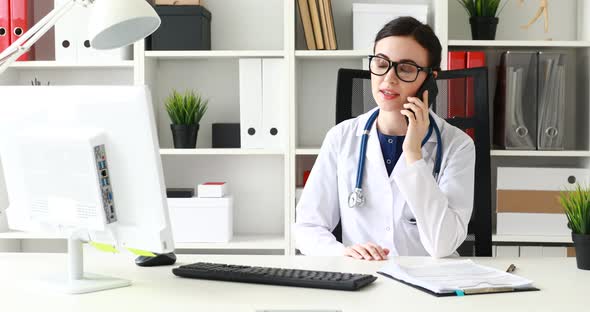 Doctor Talking on Phone and Looking at Monitor
