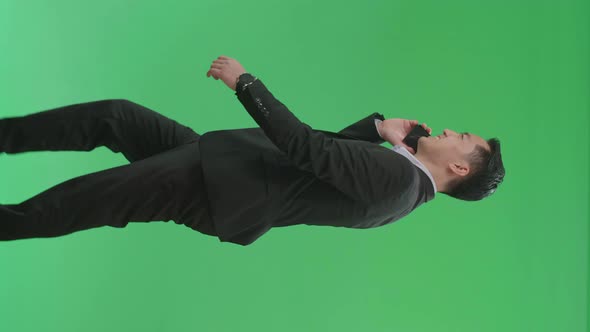Side View Of Asian Business Man Talking On Mobile Phone While Walking On Green Screen Chroma Key alt