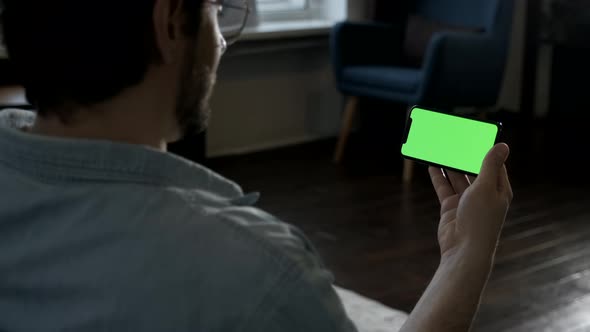 Close-up Portrait of A young man with Glasses Looking at a Smartphone, Online Applications alt