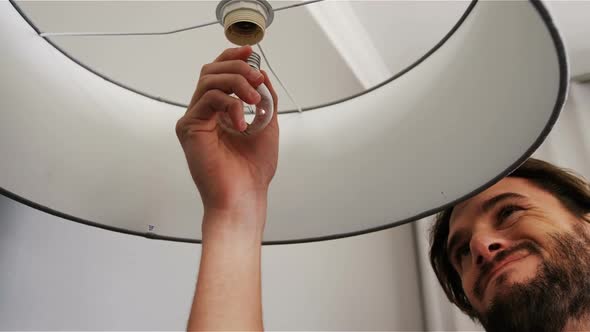 Man installing a bulb in living room alt