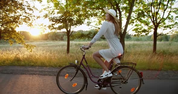 Woman Riding Bicycle on Countryside Road Sunset