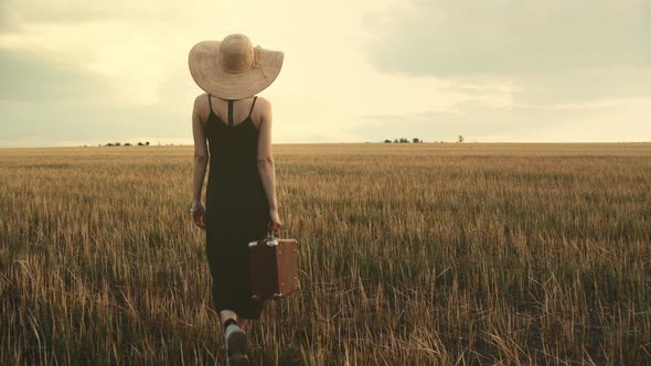 Female With A Suitcase Walking In Field