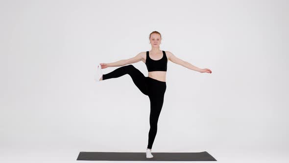 Young Flexible Woman Practicing Yoga In Studio Lifting Leg Aside alt