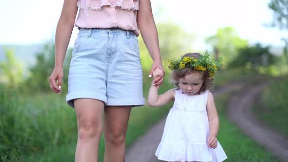 Happy Mother and Daughter with the Flower Wreath Walk in the Countryside