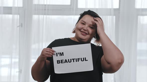 Concept Body Positivity Fat Woman Holds a Sign with the Inscription I'M BEAUTIFUL Looking in the alt