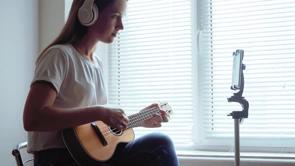 The Girl Plays the Ukulele in Front of the Window. Online Lesson