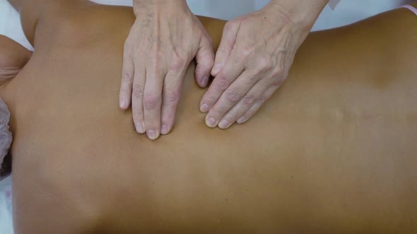 Female Hands Massage the Back of a Young Woman