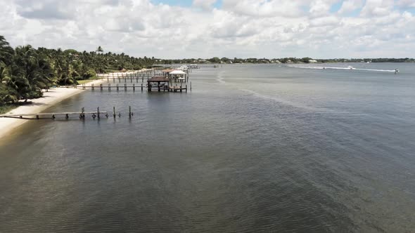 Aerial view of docks along the coastline in south florida, palm trees blowing in the breeze alt