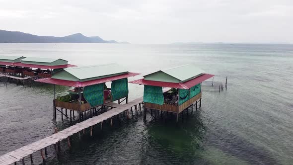 Drone Fly Over a Pier in Asia with Local Restaurant and a Boat Moving in the Sea alt
