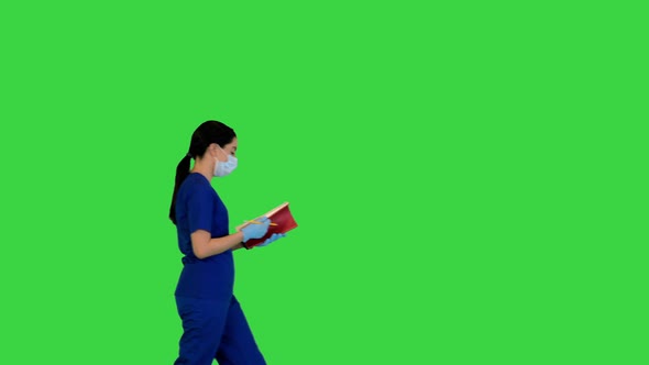 Young Indian Female Doctor Walks with Notebook on a Green Screen Chroma Key alt