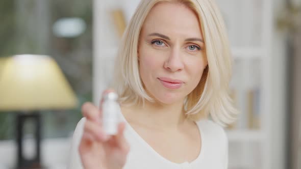Rack Focus Headshot of Beautiful Slim Caucasian Woman Smiling at Camera Holding Covid19 Vaccine in alt
