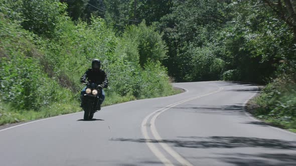 Tracking shot of man riding motorcycle on country road.  Fully released for commercial use.