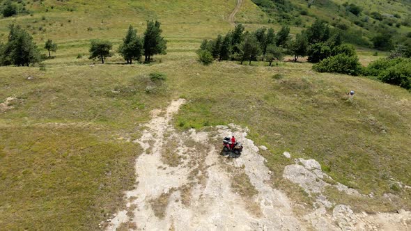 Man in a Black Cap and Red T-shirt on a Colored ATV Rides alt
