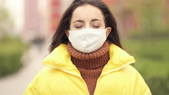 Woman with face mask sneezing at the elbow.