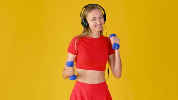 Young Girl in Sportswear with Headphones Exercising with Dumbbells