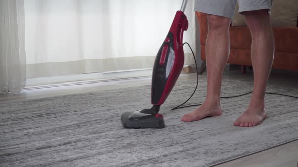 A Man Vacuums the Carpet in the Room