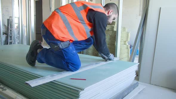 Male Builder Measuring and Cutting Gypsum Panel