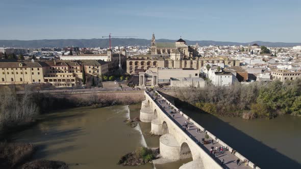 People walking on Cordoba Roman bridge, Spain. Aerial sideways