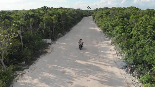 Aerial Vision of a Man and Woman Riding a Scooter Along a Country Jungle Road