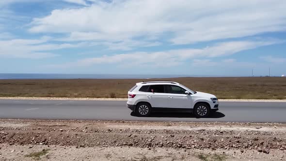 Copter Tracks a White Car Driving on a Road in the Steppe. Summer of the Steppe Landscape alt