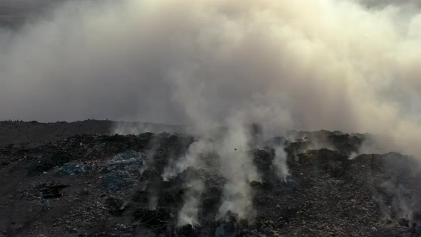 Aerial view of burning garbage pile in trash dump or landfill alt