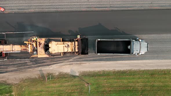 Birds eye view of asphalt paver laying blacktop and dump truck ...