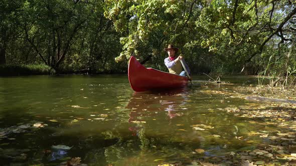 Cowboy in a Canoe Floats on the River in the Forest alt