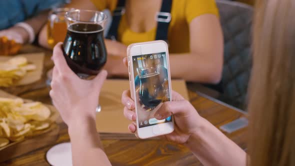 Girl taking a photo of glass with ale