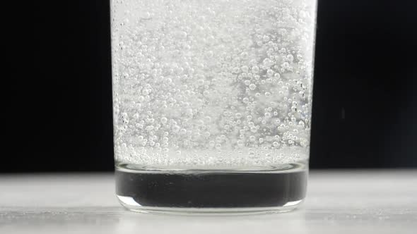 Effervescent aspirin tablet dropping to glass of water. Slow motion fizzy pill falls and dissolves w