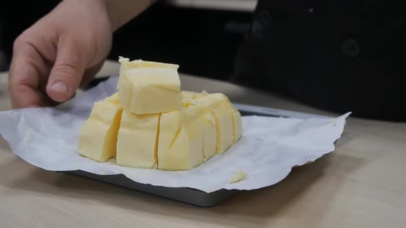 Man Chef Weighs Creamy Margarine or Butter Cut Into Pieces on a Scale