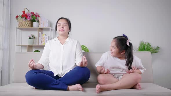 Mom and kid having meditation activity on the weekend together. Kid laughing mom alt