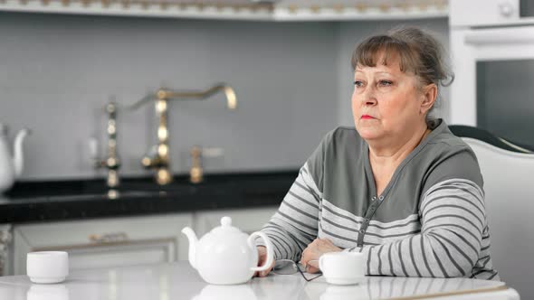 Lonely Wistful Unhappy Senior Lady Sitting on Table Having Coffee Break Have Depressed Emotion alt