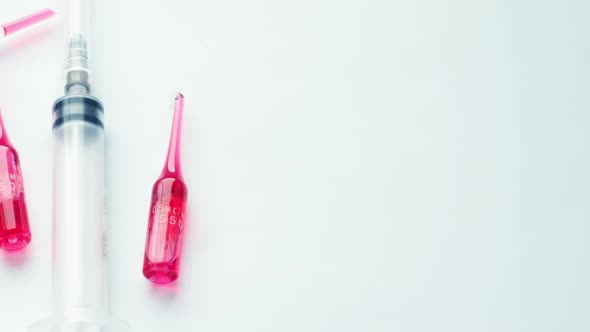 Slow Motion Syringe Lying Pastel Blue Background with Group Glass Ampoules with alt