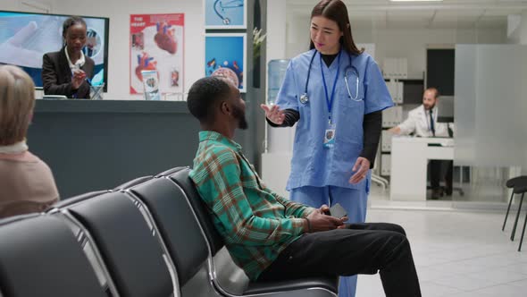 African American Patient Going in Medical Office with Asian Nurse