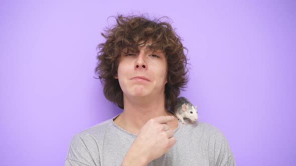 A Young Guy with Curly Hair Smiles at the Camera on an Isolated Background a Pet Rat is Sitting on alt