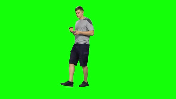 Young Male Walking and Watching on the Phone Something, Drinking Coffee. Chroma Key alt