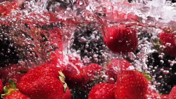 Slowmotion Falling Strawberries Into the Water on a Black Background