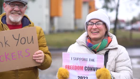 A Man and a Woman in Warm Clothes Hold Signs with the Inscriptions Thank you Truckers and Freedom alt